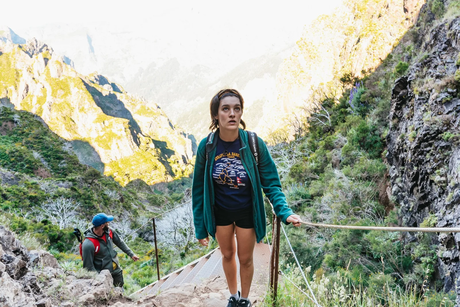 A hiker on the PR1 path between steep rock walls on the way to Pico Ruivo