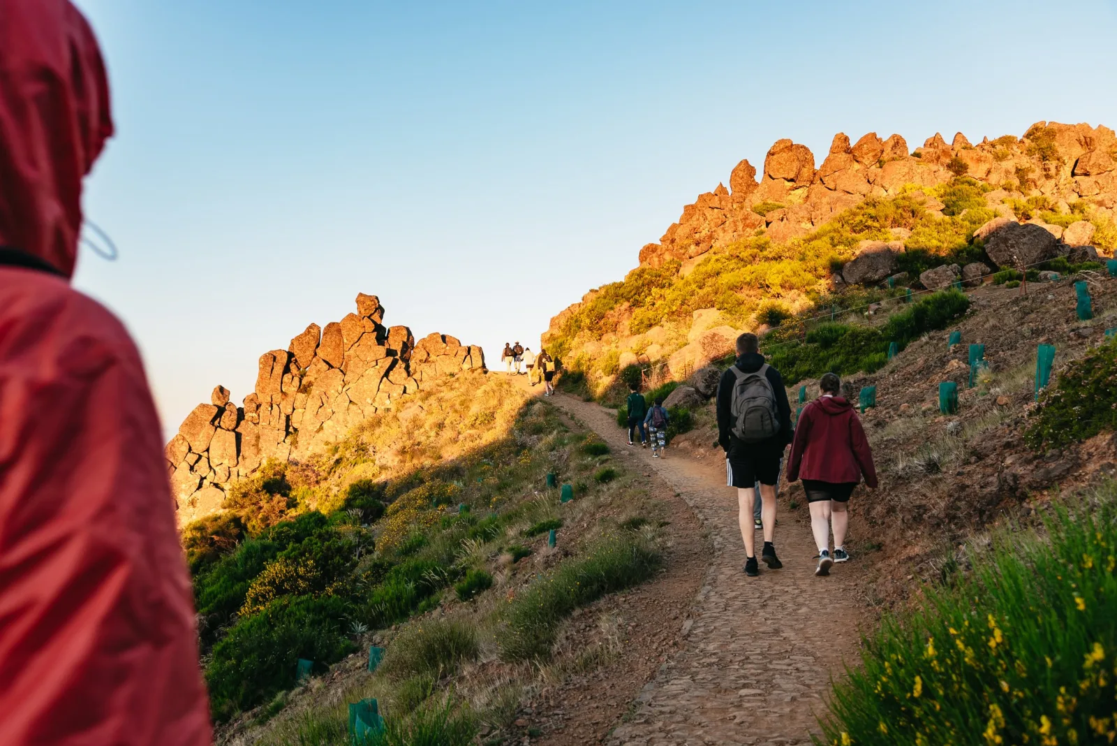 Hikers on the stone trail below the Arieiro pinnacles in early morning light