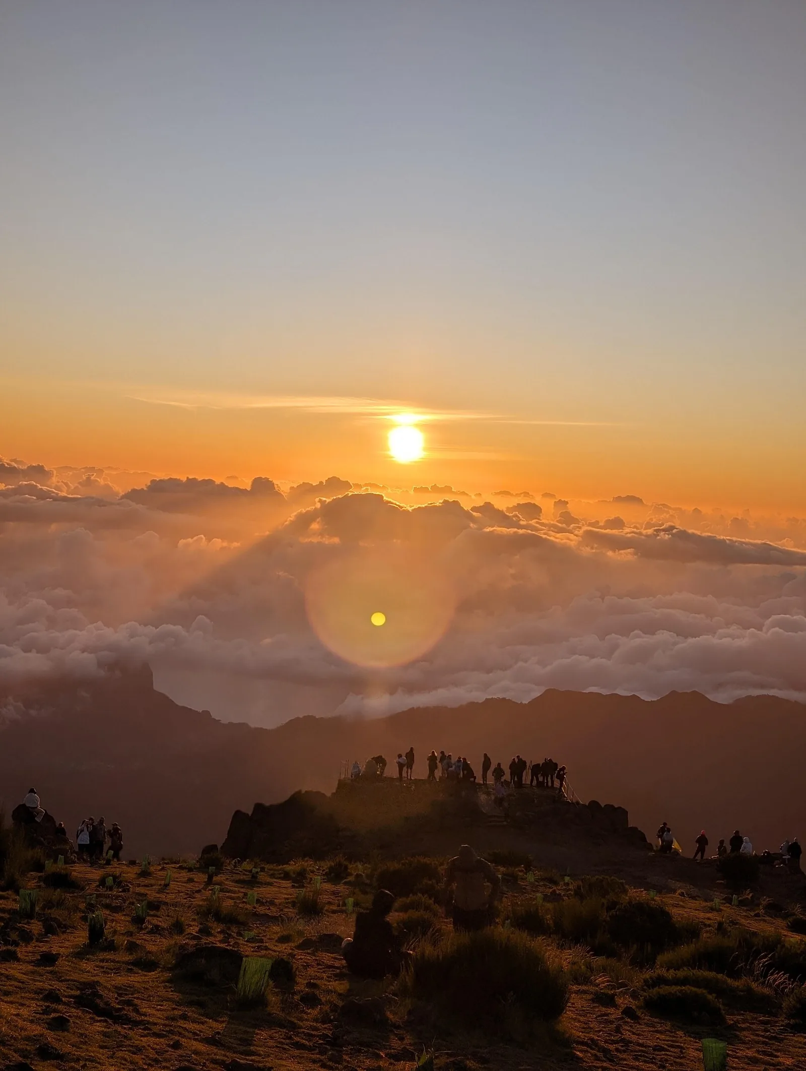 The sun rising through cloud above the peaks, seen from the Arieiro viewpoint