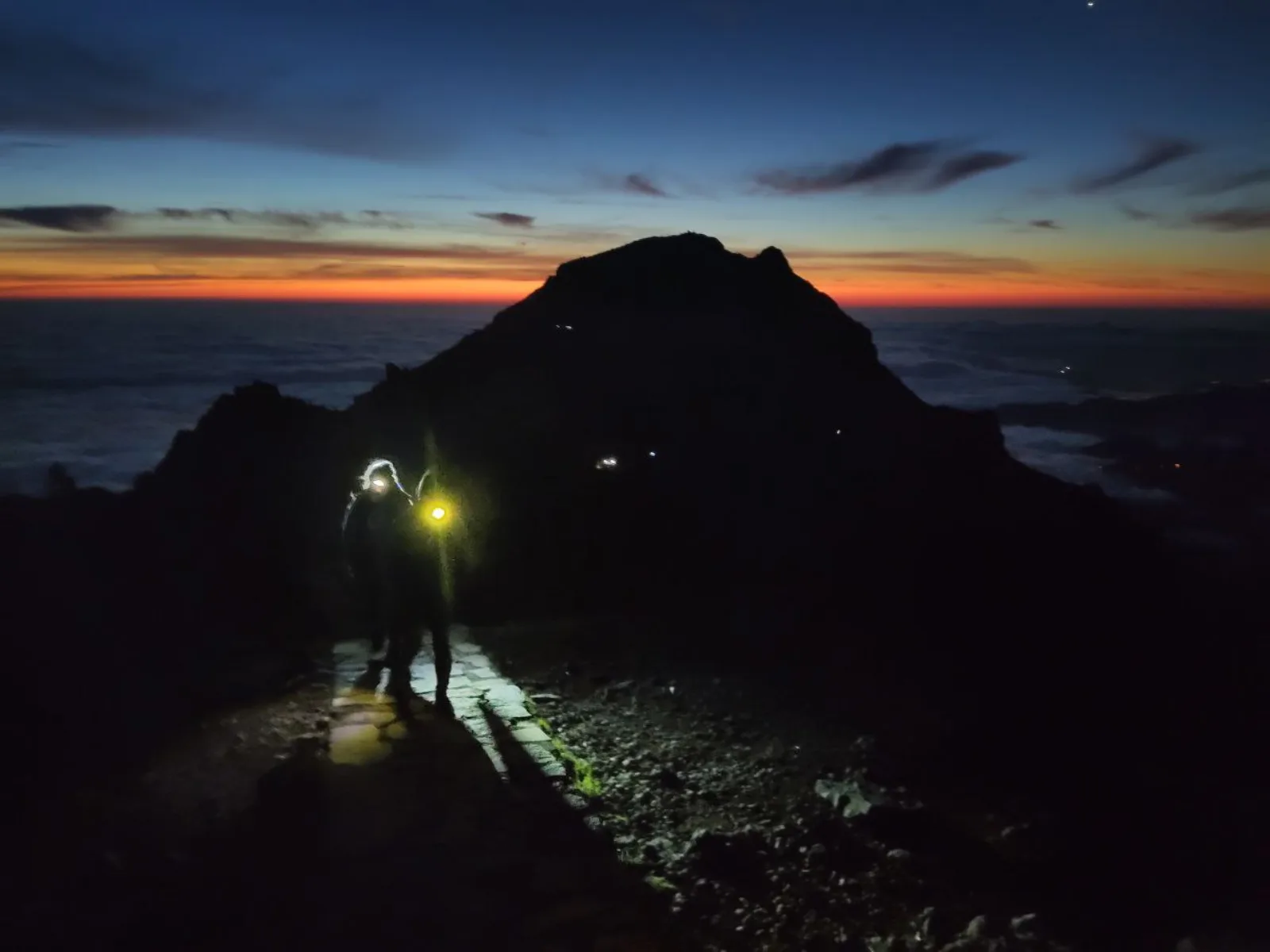 Hikers climbing by headtorch in the dark before dawn