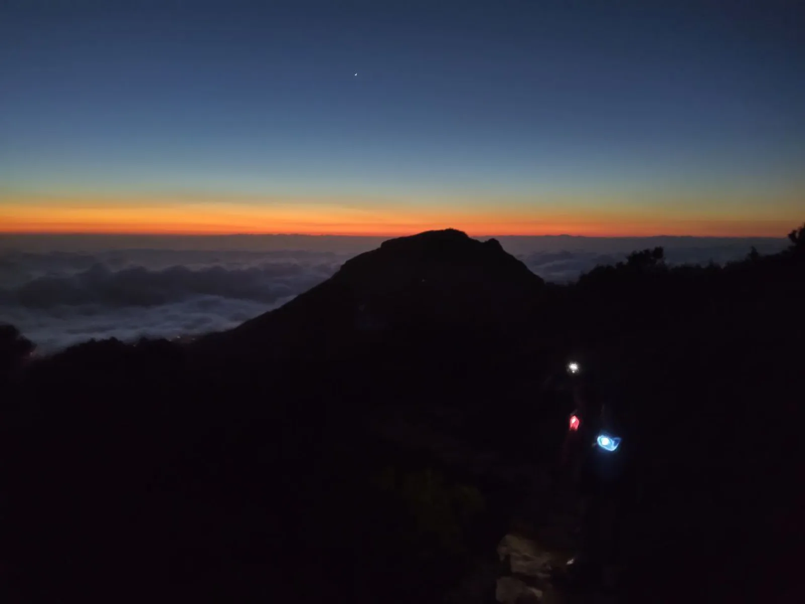Pre-dawn colour over the peaks, with headtorches moving on the trail below