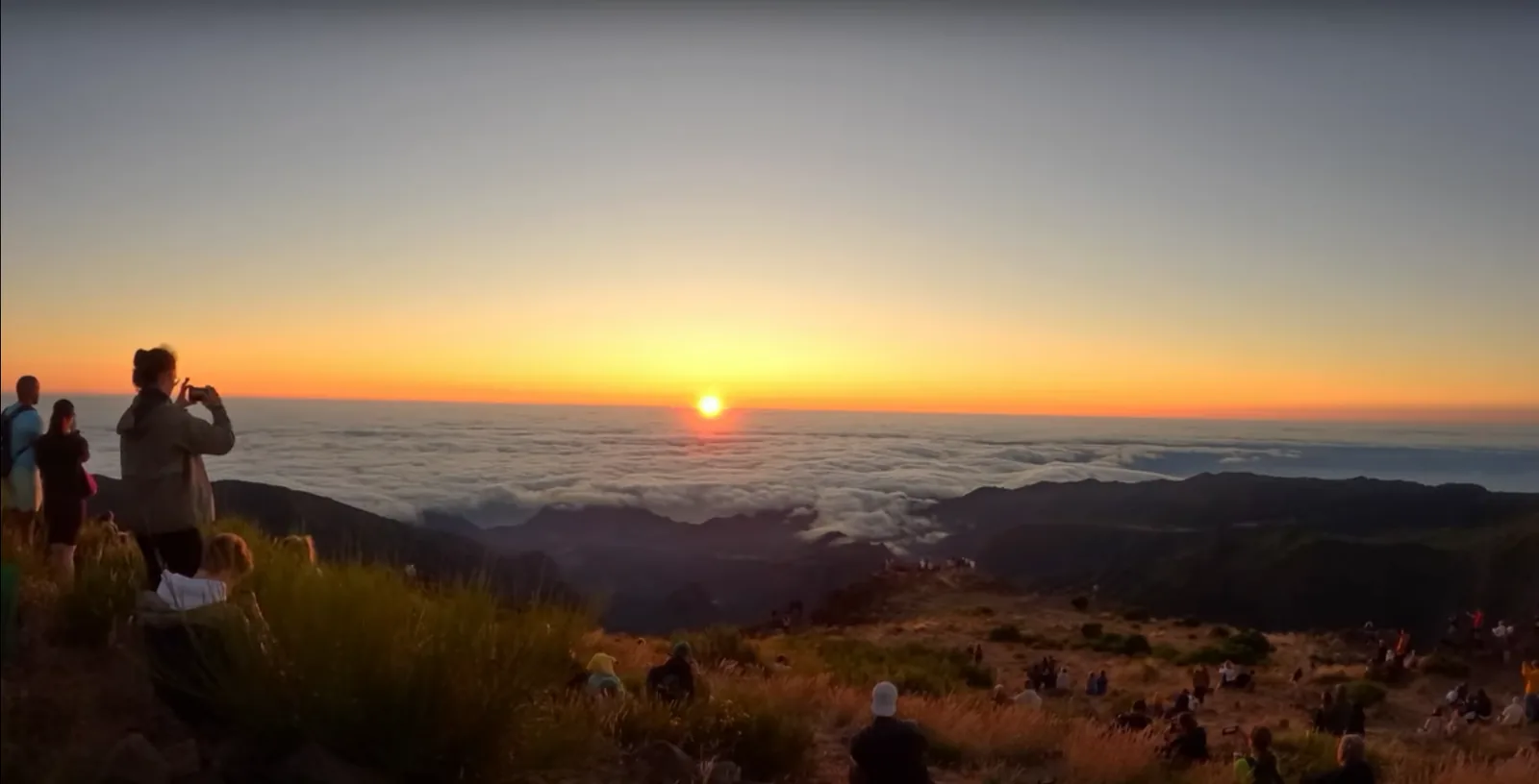 Sunrise over the cloud layer at Pico do Areeiro, with walkers watching from the ridge